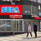 Pedestrians walk in front of the yet-opened Sega arcade.